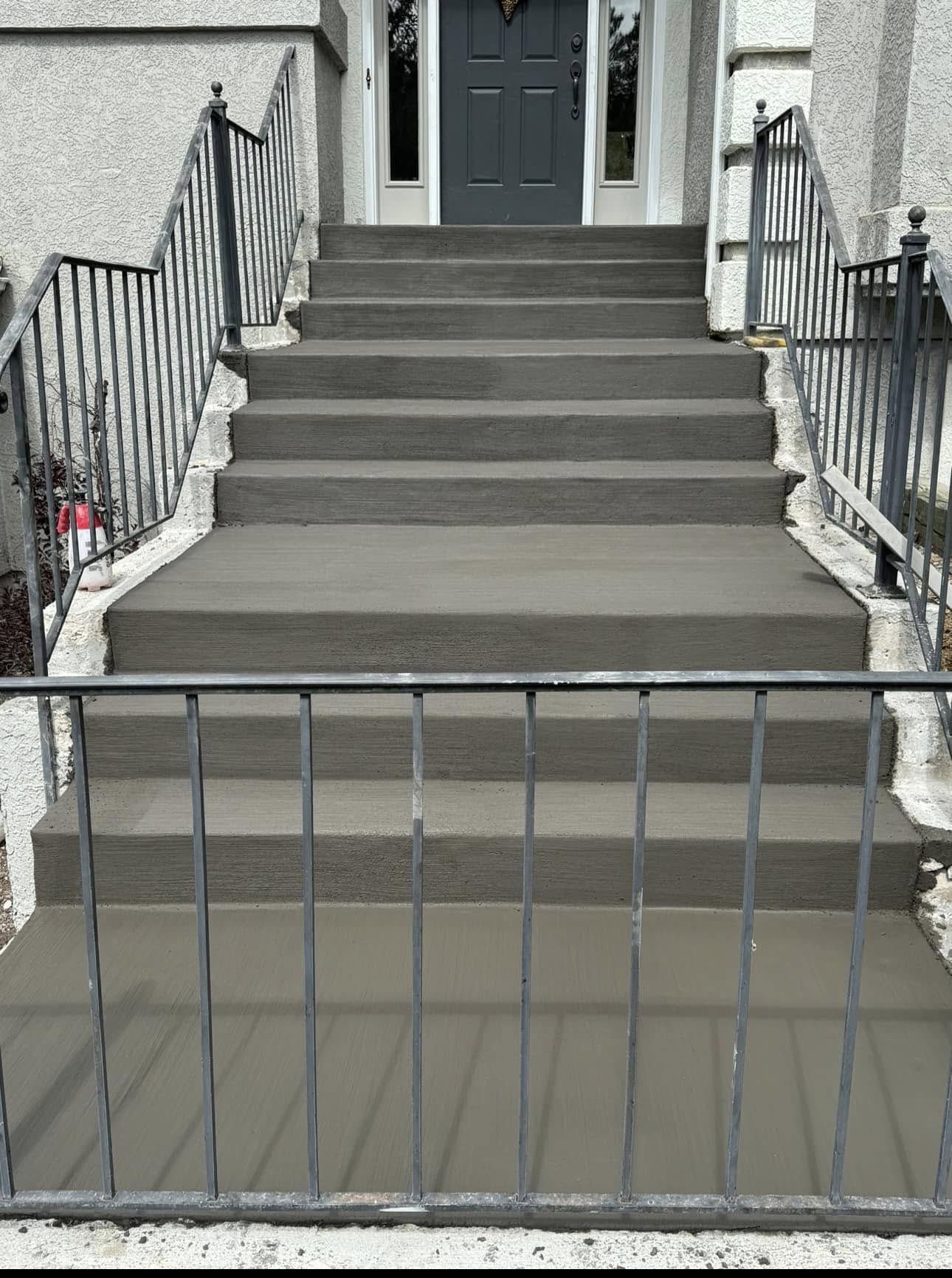 Newly poured broom finished concrete front steps with iron railings